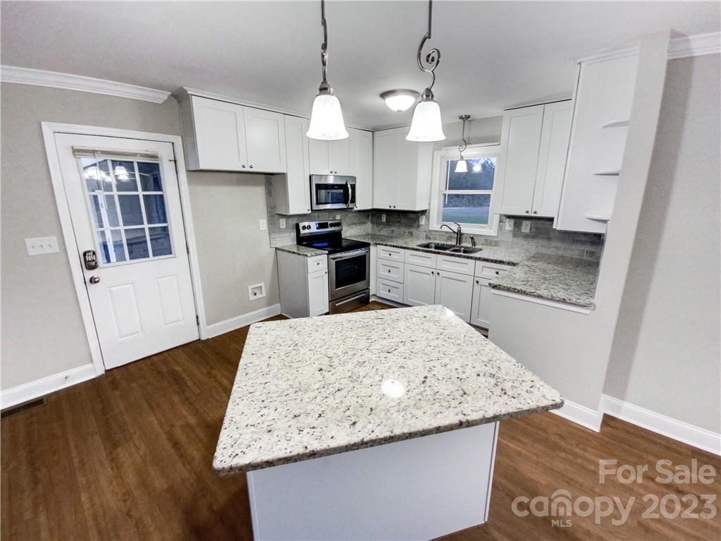 3020 Potter Road Waxhaw, NC 28173 - Photo 2 of 17 a kitchen with granite countertop wooden cabinets a sink a stove and kitchen island
