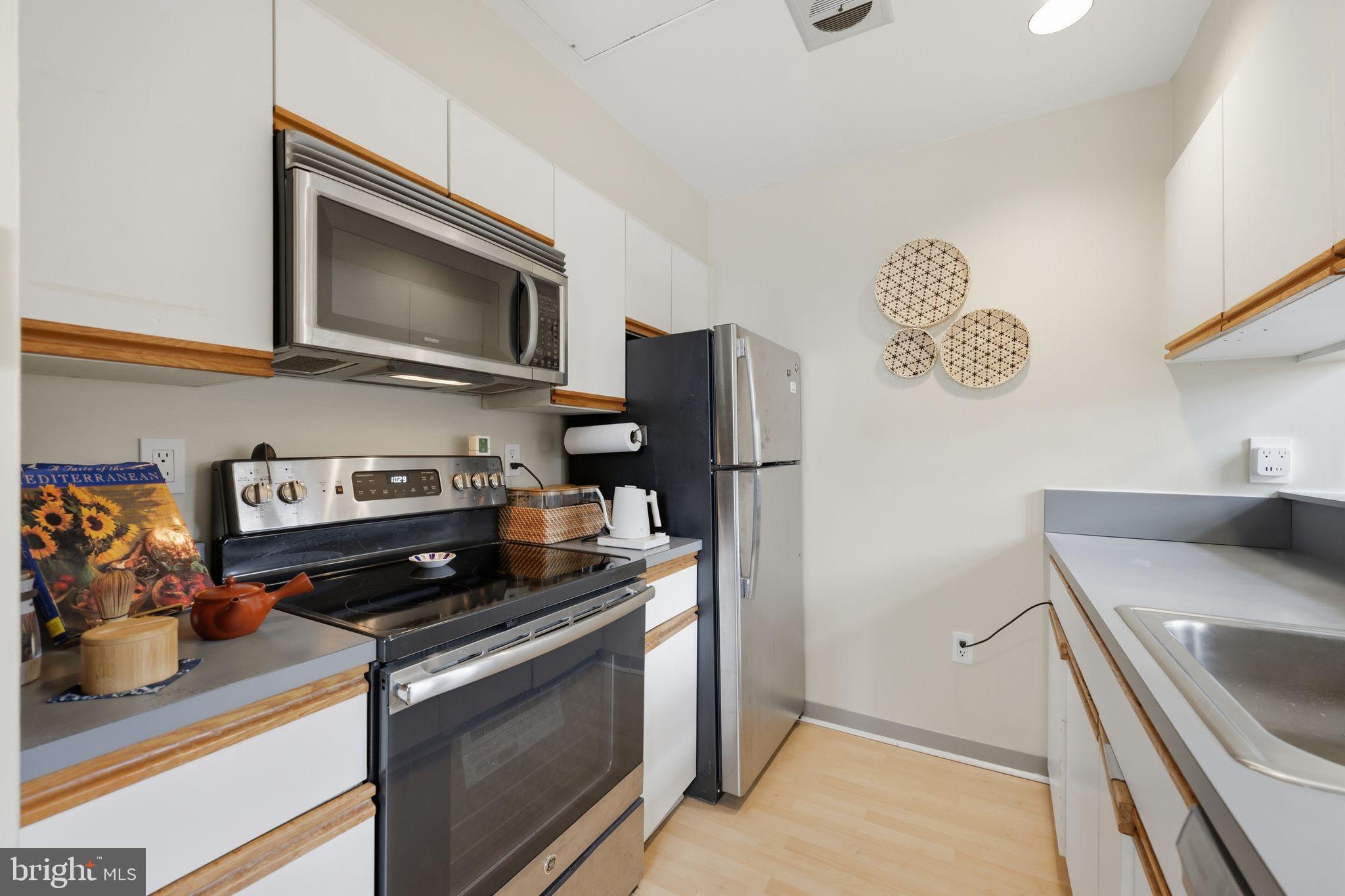 1601 Spring Garden Street, Unit 207 Philadelphia, PA 19130 - Photo 6 of 20 a kitchen with stainless steel appliances granite countertop a refrigerator stove and microwave