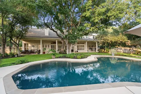 a view of a house with pool fire pit a yard and lawn chairs with plants