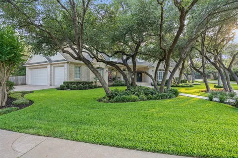 a view of a house with a big yard and large trees
