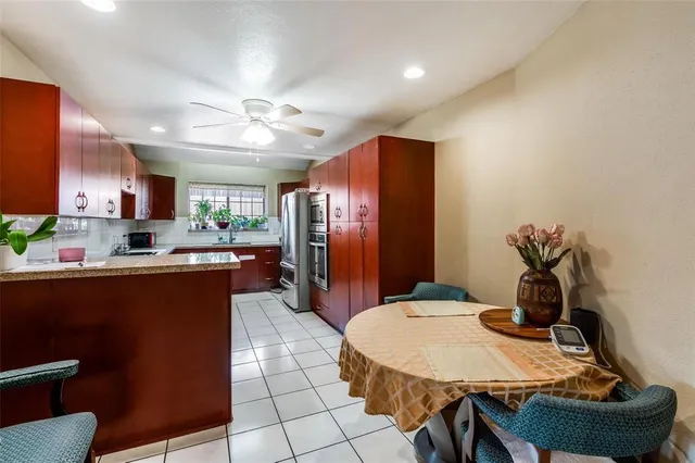a kitchen with stainless steel appliances granite countertop a refrigerator a sink a stove a dining table and chairs