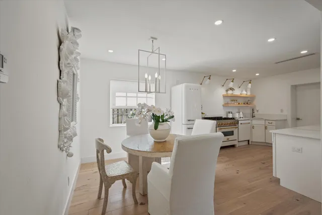 a large white kitchen with a stove a sink a refrigerator and chandelier