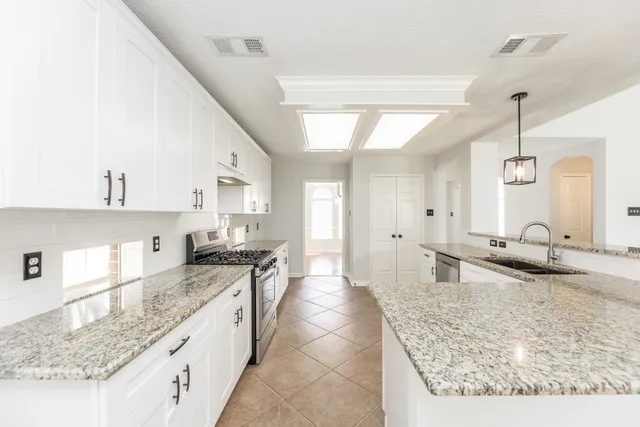 a kitchen with granite countertop a sink a counter top space and cabinets