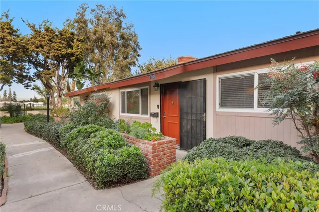 a white house with a small yard and large trees