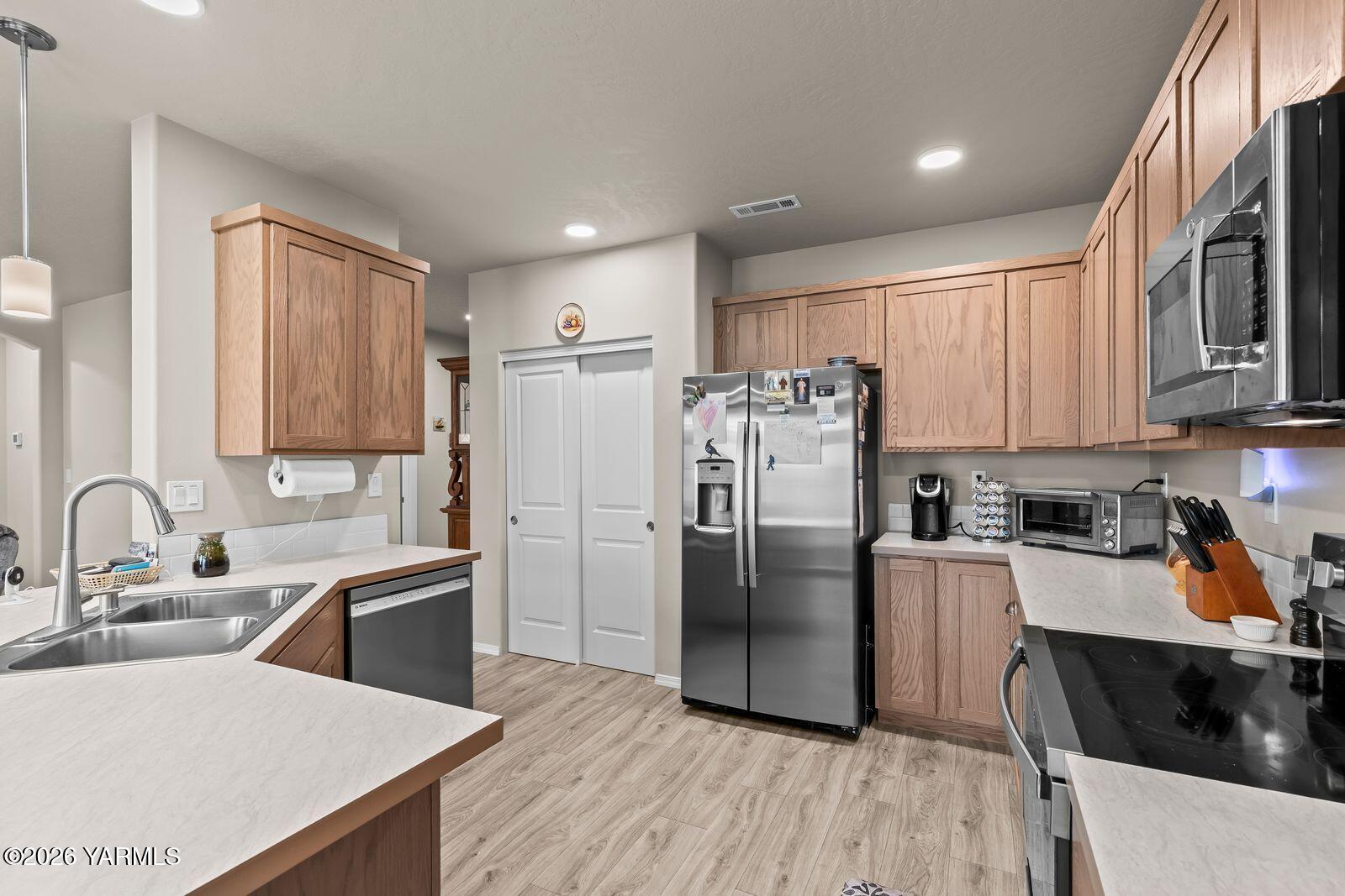 403 Lambert Court Grandview, WA 98930 - Photo 8 of 27 a kitchen with stainless steel appliances a refrigerator a sink a stove a microwave and wooden floors