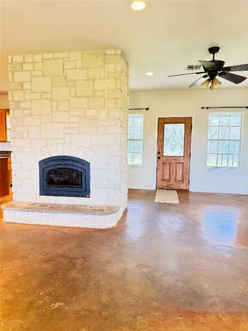a view of an empty room with a fireplace and a ceiling fan