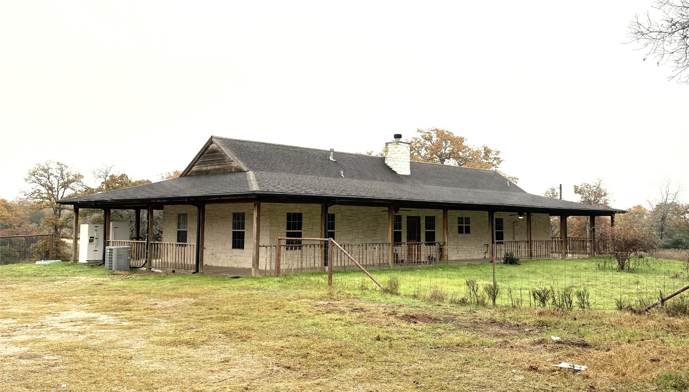 11791 Silver Springs Road Rockdale, TX 76567 - Photo 2 of 28 Rear view of property featuring a chimney, a yard, stone siding, and covered porch