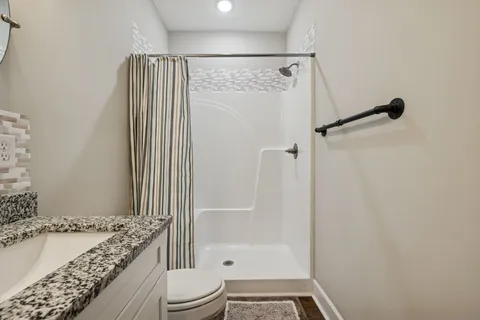 a bathroom with a granite countertop bathtub shower sink and toilet