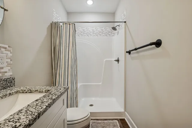 a bathroom with a granite countertop bathtub shower sink and toilet