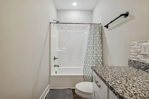 a bathroom with a granite countertop toilet a sink and a shower