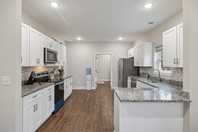 a large kitchen with granite countertop a large counter top stainless steel appliances and cabinets
