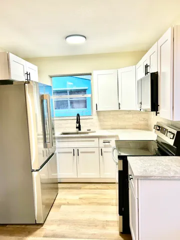 a kitchen with stainless steel appliances granite countertop a sink and a refrigerator