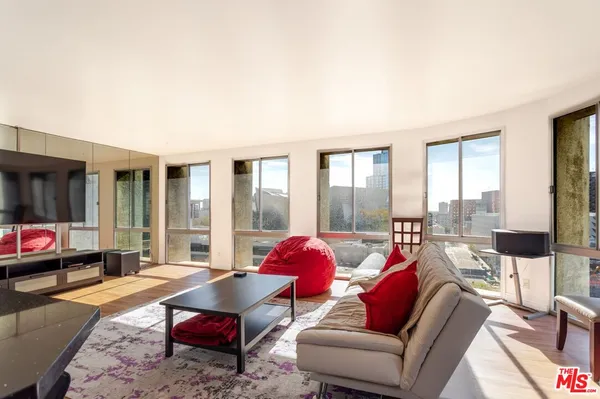 a living room with furniture a rug and a dining table with wooden floor