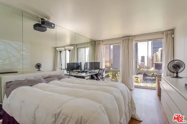 a bedroom with a bed a desk and a potted plant