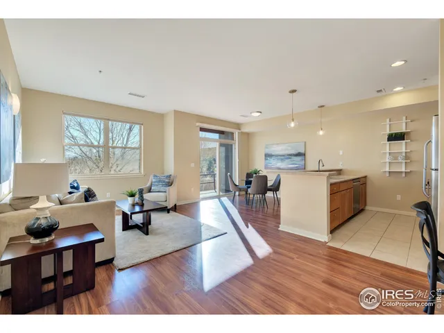 a living room with furniture dining table wooden floor and a large window