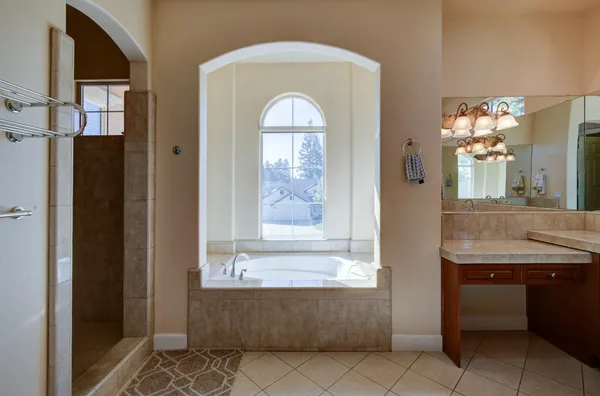 a bathroom with a granite countertop bathtub sink vanity and mirror