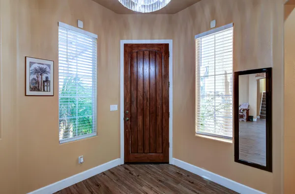 an empty room with wooden floor closet and windows