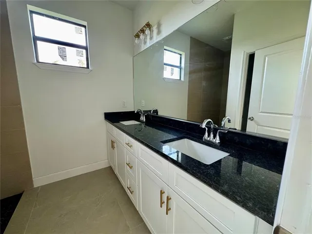 a bathroom with a granite countertop sink and a mirror