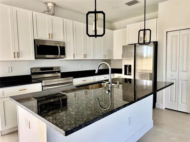 a kitchen with stainless steel appliances granite countertop a sink a stove and a refrigerator