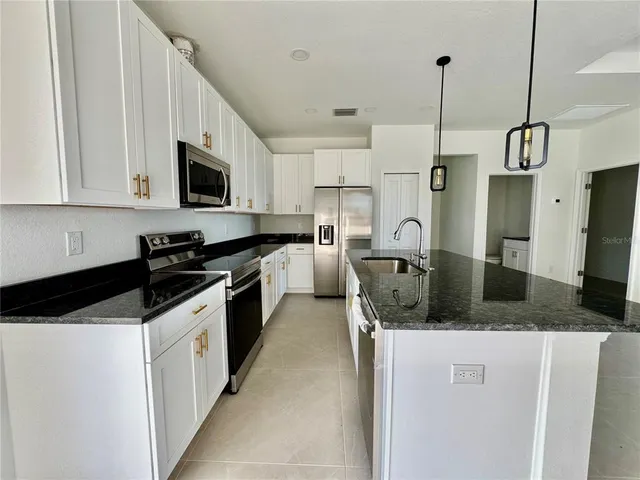 a kitchen with stainless steel appliances granite countertop a sink a stove and a refrigerator