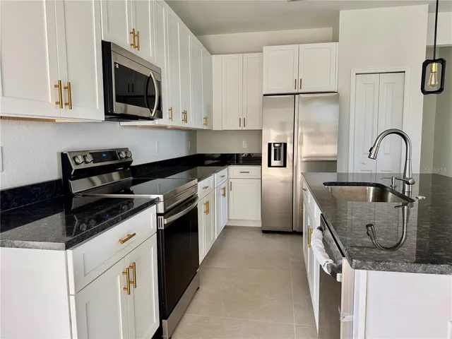 a kitchen with stainless steel appliances granite countertop a sink stove a refrigerator a microwave and cabinets