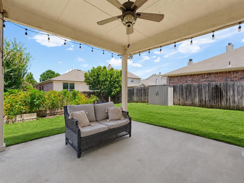 13268 Fencerow Road Fort Worth, TX 76244 - Photo 22 of 25 Covered patio with string lighting, a ceiling fan, concrete flooring, and an expansive lawn area