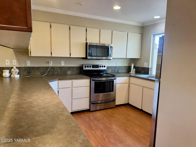 a kitchen with granite countertop a sink a stove and cabinets