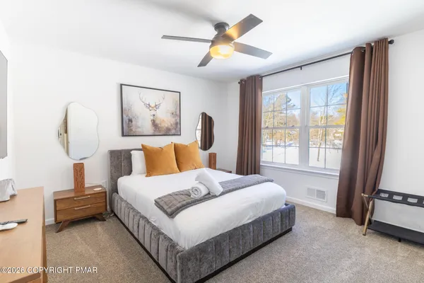 a bedroom with a bed a window and painting on the wall