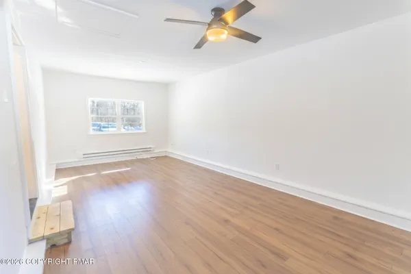 an empty room with wooden floor and window