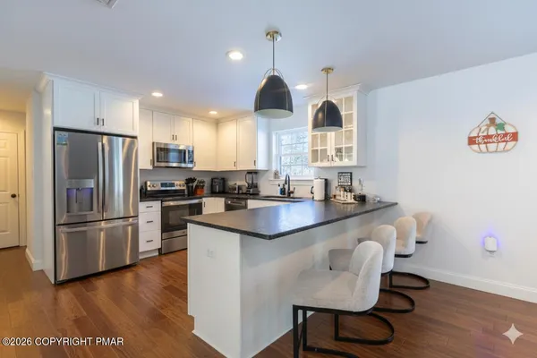 a kitchen with granite countertop a refrigerator a stove a sink and a stove