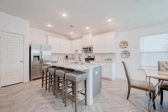 a kitchen with a table chairs microwave and refrigerator