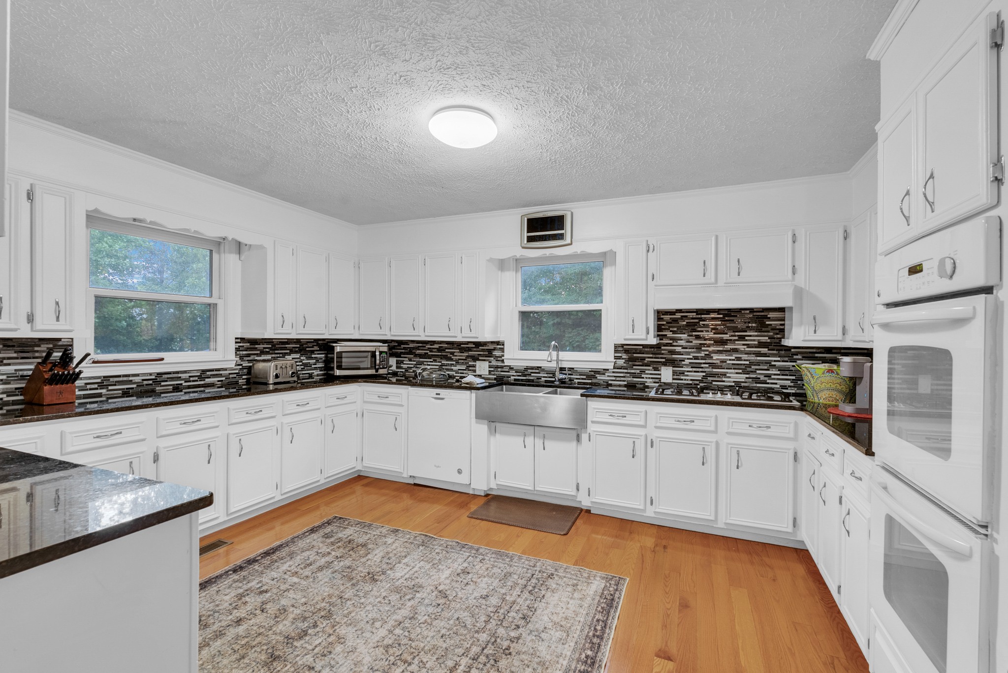 a kitchen with stainless steel appliances granite countertop a stove a sink and white cabinets