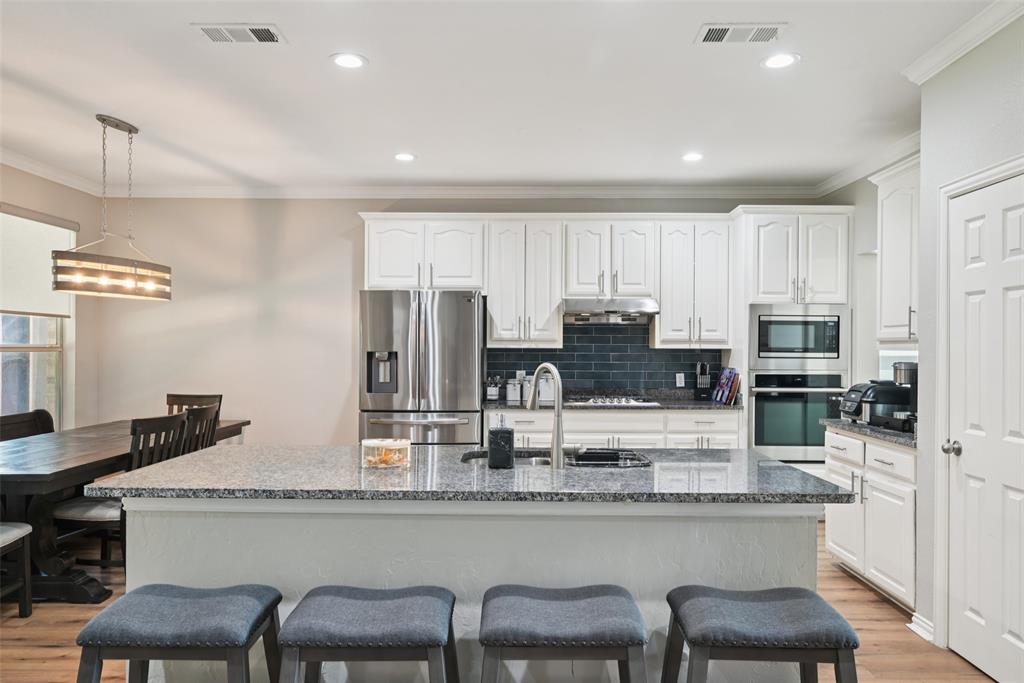 1321 Shell Beach Drive Little Elm, TX 75068 - Photo 11 of 40 a kitchen with stainless steel appliances granite countertop a table chairs refrigerator and sink