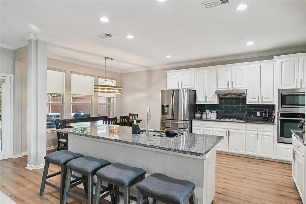 1321 Shell Beach Drive Little Elm, TX 75068 - Photo 12 of 40 a kitchen with stainless steel appliances granite countertop a stove top oven a refrigerator a sink and chairs