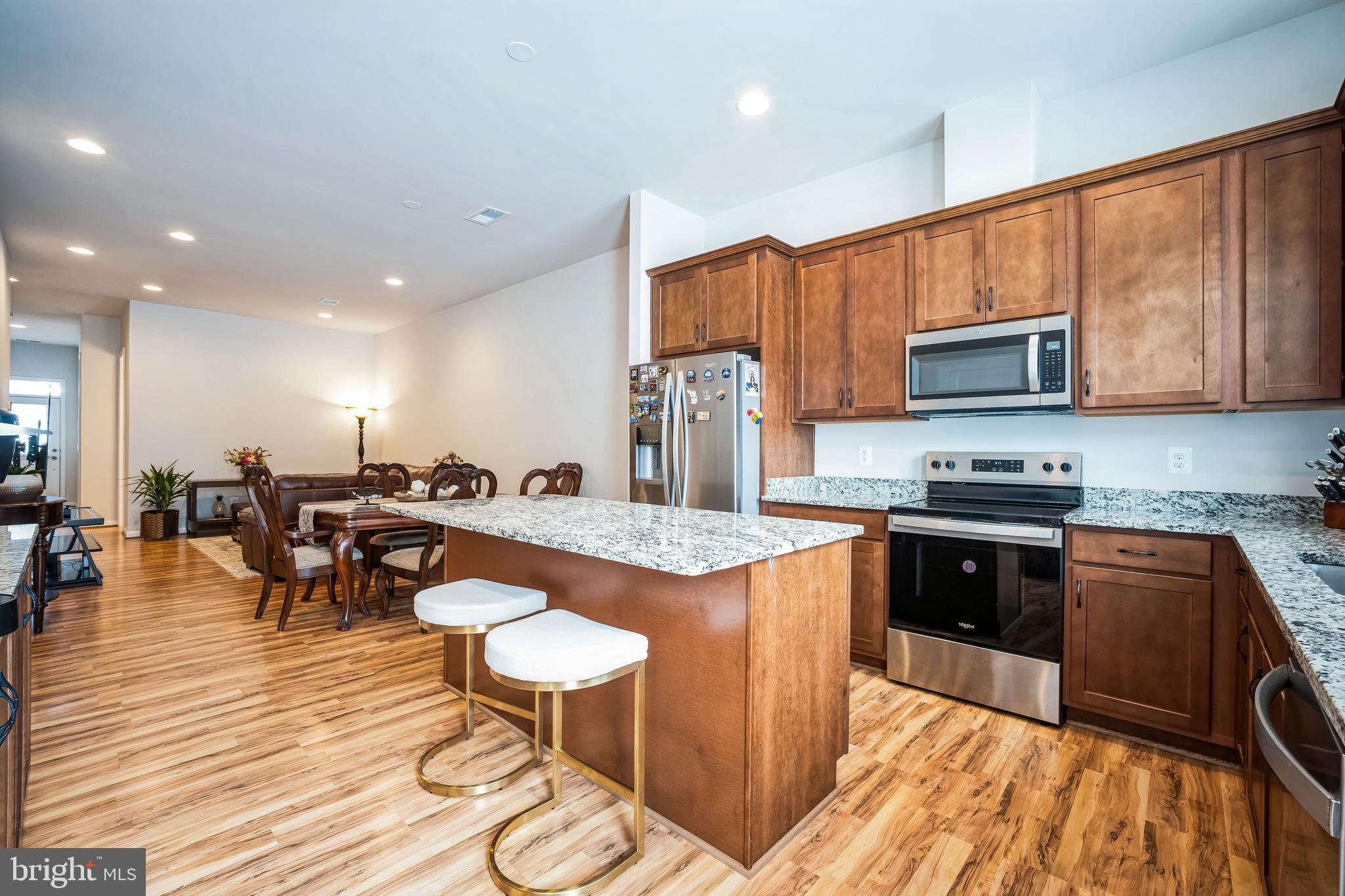 9348 Crestview Rdg Drive Bristow, VA 20136 - Photo 9 of 29 a kitchen with stainless steel appliances granite countertop a stove top oven a sink dishwasher a dining table and chairs with wooden floor