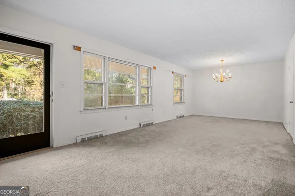 an empty room with chandelier fan and windows