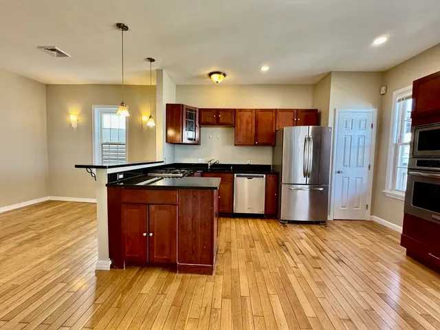 a kitchen with stainless steel appliances granite countertop a refrigerator a sink and a stove