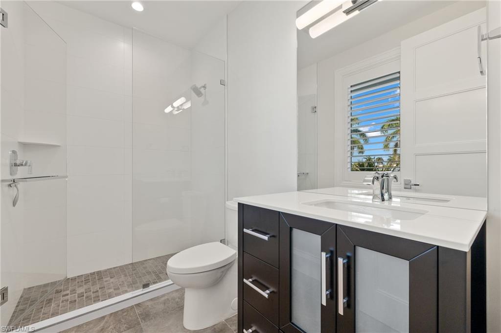 2649 Tarpon Road Naples, FL 34102 - Photo 40 of 50 a bathroom with a granite countertop sink a toilet and a mirror