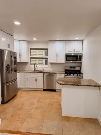 a kitchen with stainless steel appliances granite countertop a stove a sink dishwasher a refrigerator and a microwave