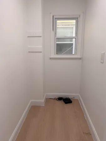 an empty room with wooden floor and windows with curtains