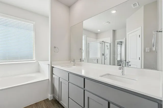 a bathroom with a sink double vanity granite tub shower and a mirror