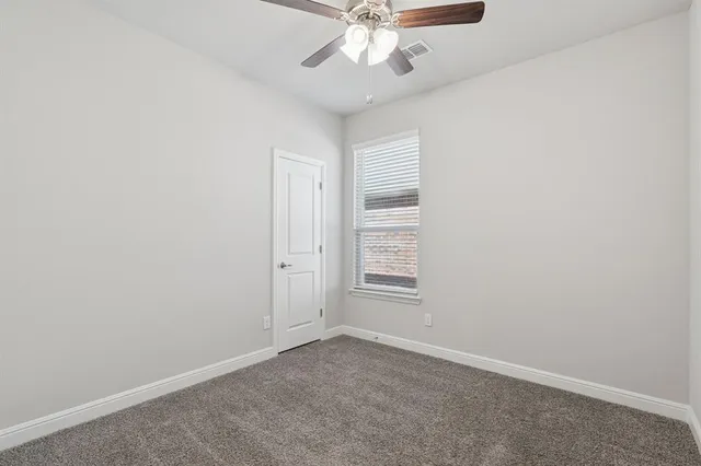 an empty room with chandelier fan and windows