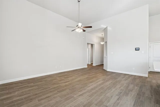 an empty room with wooden floor ceiling fan and window