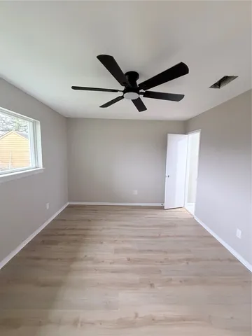 a view of an empty room with window and ceiling fan