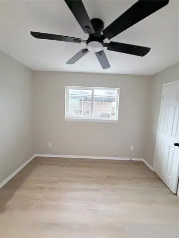 an empty room with a window and a ceiling fan
