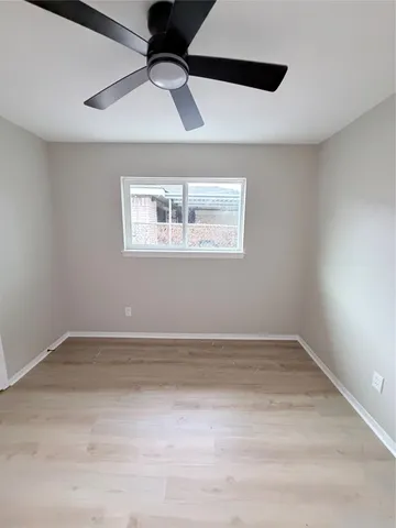 an empty room with a ceiling fan and windows