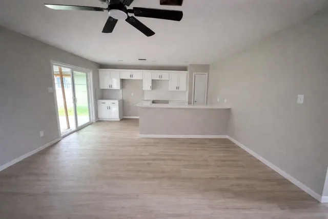 a view of empty room with wooden floor and window