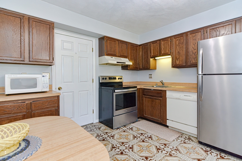 23 Tamarack Lane, Unit 23 Peabody, MA 01960 - Photo 15 of 42 a kitchen with a refrigerator sink and wooden cabinets