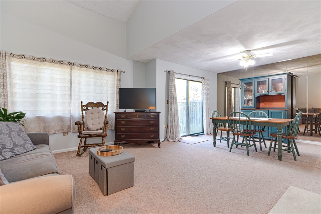 23 Tamarack Lane, Unit 23 Peabody, MA 01960 - Photo 9 of 42 a living room with furniture a dining table and a floor to ceiling window