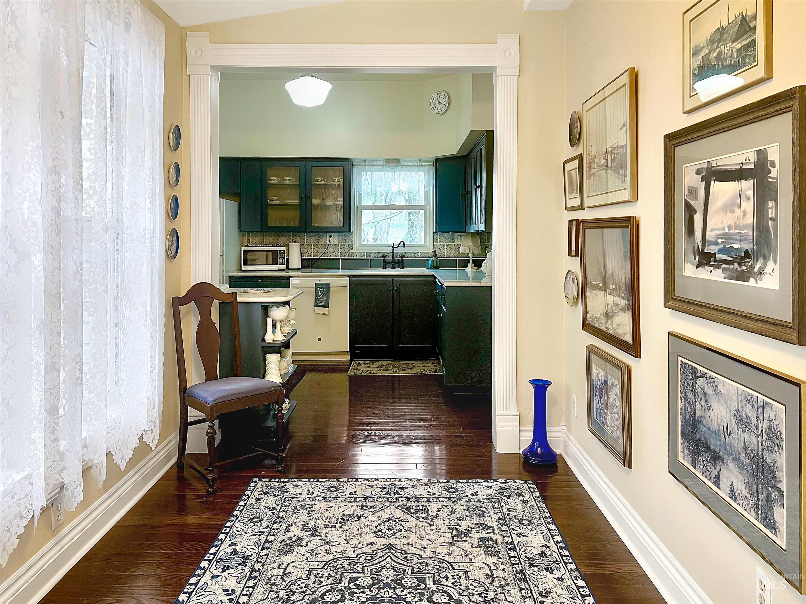 516 East Main Street Weiser, ID 83672 - Photo 17 of 50 Sunroom leading to kitchen with light countertops, dark wood-type flooring, white appliances, tasteful backsplash, and glass insert cabinets